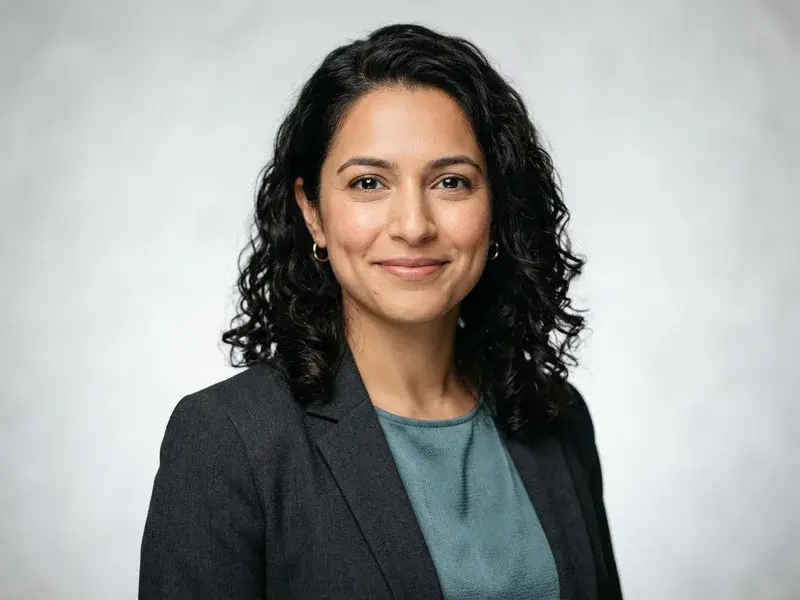 Portrait professionnel d'une femme souriante, fond studio clair, style épuré et moderne, pour un CV de haute qualité.
