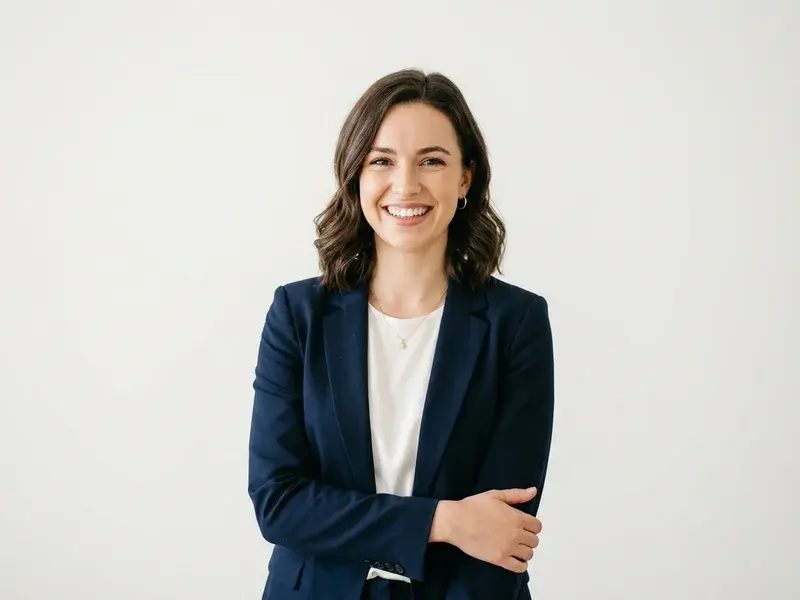 Jeune femme souriante et professionnelle, regard confiant, posant pour un portrait de studio de haute qualité sur un fond lumineux et épuré.