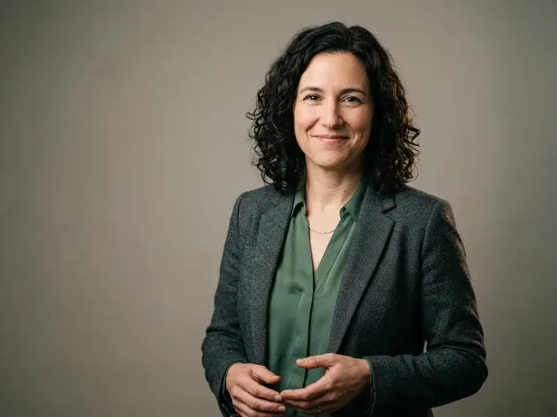 Portrait professionnel hyper-réaliste d'une personne en reconversion, souriante et confiante, avec un éclairage doux et un fond neutre de studio.